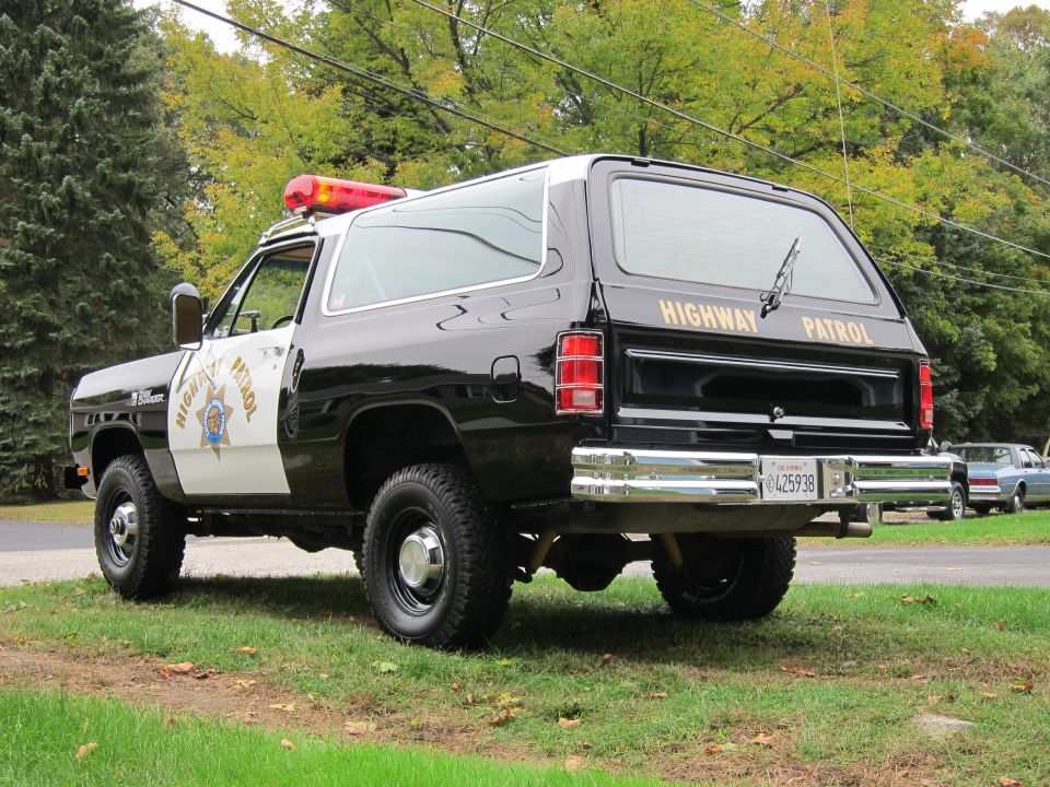 1987 Dodge Ramcharger police vehicle with 'HIGHWAY PATROL' on rear tailgate. Another car is parked behind it