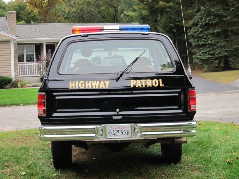 1987 Dodge 1500 - This black SUV, marked 'HIGHWAY PATROL', features a light bar on its roof and a California license plate.
