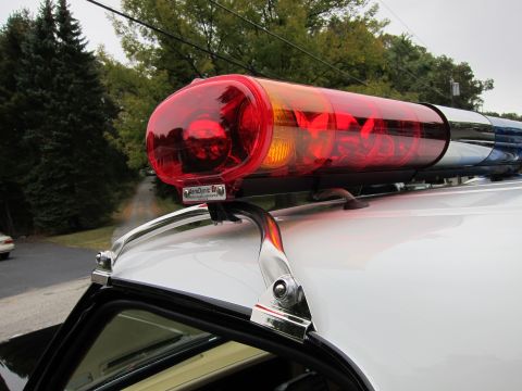 1987 Dodge 1500 - Close-up of a light bar mounted on the roof of a white vehicle, with trees and a road in the background.
