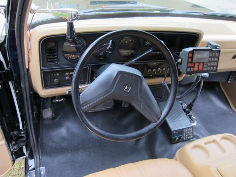 1987 Dodge 1500 - The interior of a vehicle shows a CB radio and a scanner mounted on the dashboard, along with a Chrysler steering wheel emblem.