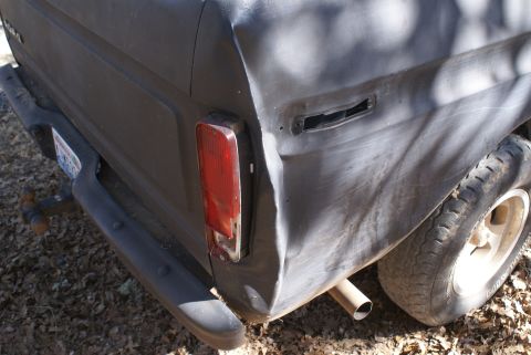 1978 Ford Bronco - The rear quarter panel of a truck shows damage and a missing fuel door.