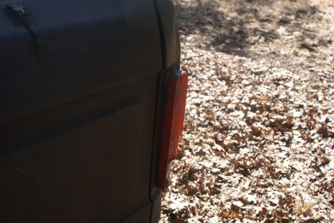 1978 Ford Bronco - Close-up of a dark vehicle's rear quarter panel and taillight, with a watermark for Super Motors.