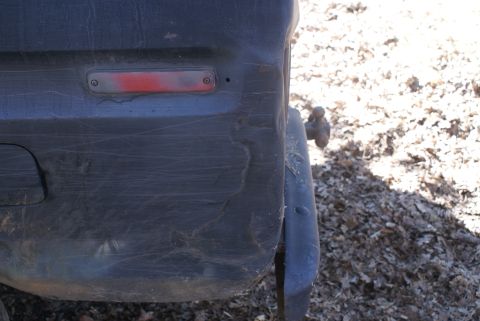 1978 Ford Bronco - Close-up of a vehicle's rear corner, revealing a damaged bumper and a visible tow hitch.