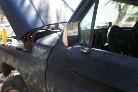 1978 Ford Bronco - Driver's side view of a black 1978 Ford Bronco, showing the interior and the open hood.