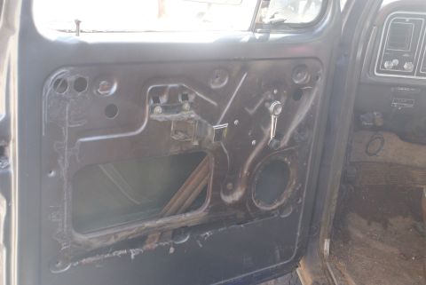 1978 Ford Bronco - The interior of a vehicle door panel is shown, revealing the window regulator and speaker mounting hole.