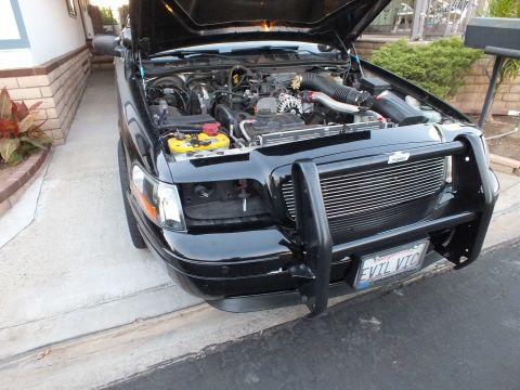 2003 Ford Crown Victoria - Front of a black sedan with raised hood and a tubular brush guard, plate reads EVIL VIC.