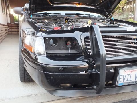 2003 Ford Crown Victoria - Front-left of a black sedan with headlight assembly out and a tubular guard installed.