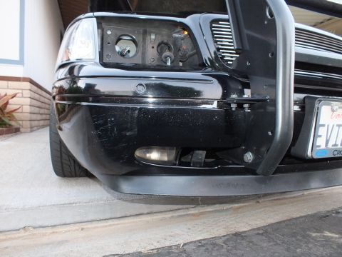 2003 Ford Crown Victoria - Lower front bumper of a black sedan with round fog lamp and tubular guard in driveway.