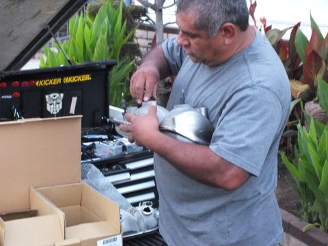2003 Ford Crown Victoria - Person holds shiny metal components near a tool chest decorated with audio decals.