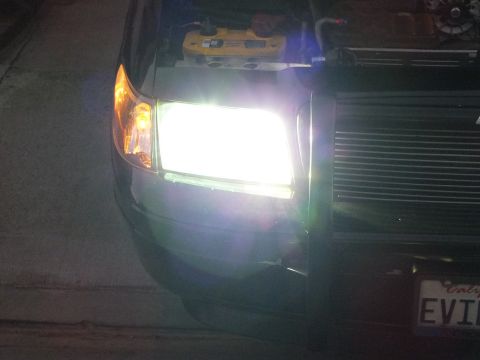 2003 Ford Crown Victoria - Driver-side HID headlight blazing on the dark Crown Victoria, billet grille and plate edge at right