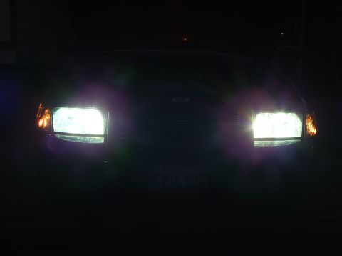 2003 Ford Crown Victoria - Near-black night shot framing both glowing HID headlights of the EVIL VIC Crown Victoria