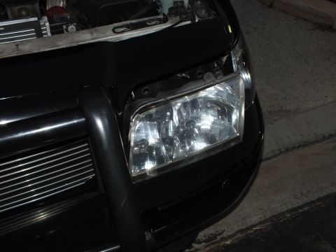 2003 Ford Crown Victoria - Close night shot of the clear retrofit headlight seated in the Crown Victoria with push bar below