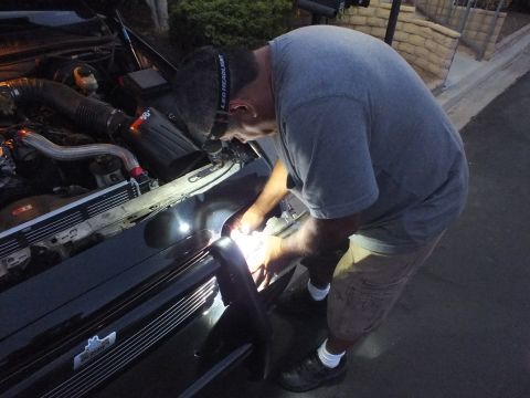 2003 Ford Crown Victoria - Man wearing an LED headlamp leaning over the Crown Victoria front, light beam on the work area