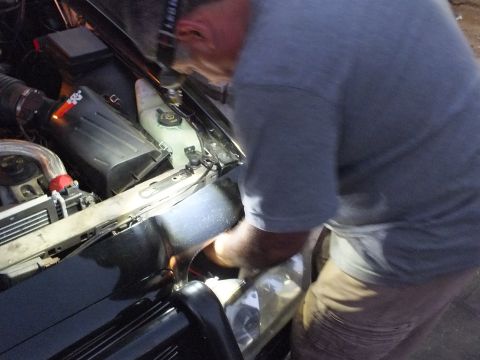 2003 Ford Crown Victoria - Man working over the open engine bay of the Crown Victoria at night, coolant tank and air box in view