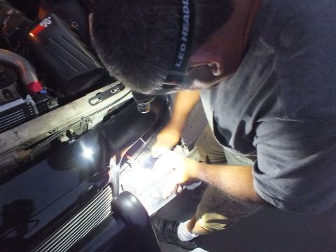2003 Ford Crown Victoria - Headlamp-lit mechanic wiping or fitting parts on the Crown Victoria front corner in the dark