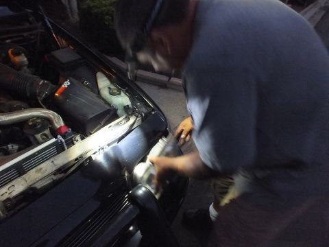 2003 Ford Crown Victoria - Nighttime repair scene as a worker leans into the engine compartment of a dark car under a worklight