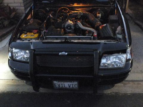 2003 Ford Crown Victoria - Black sedan with a push-bar brush guard, billet grille and EVIL VIC plate over a turbocharged engine bay