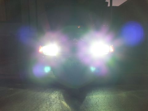 2003 Ford Crown Victoria - Front of a dark car lit up with bright high beams and lower fog lamps in the dark