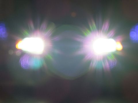 2003 Ford Crown Victoria - Two intense headlights create rainbow starburst flares in a dark nighttime close-up