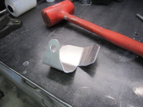 2008 Jeep Wrangler - Metal bracket and red rubber mallet on a workbench surface.
