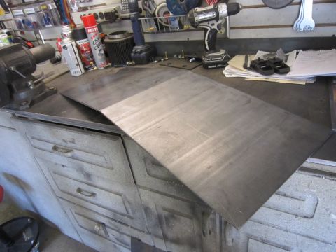 2008 Jeep Wrangler - A metal skid plate rests on a workbench, surrounded by tools and workshop supplies.