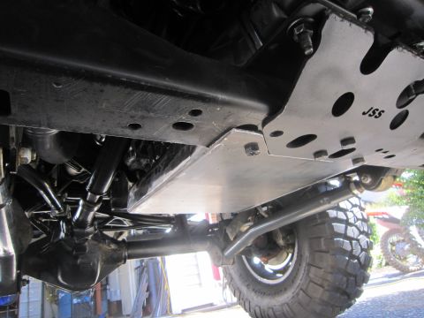 2008 Jeep Wrangler - Close-up view of aftermarket skid plates and suspension components installed on a vehicle.