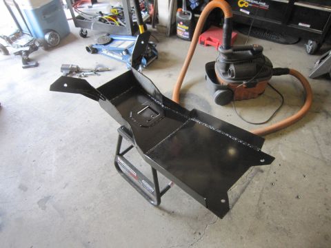 2008 Jeep Wrangler - A newly painted skid plate sits on a stand in a garage, ready for installation.