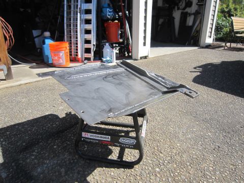2008 Jeep Wrangler - A custom fabricated metal skid plate rests on a stand outside a garage.