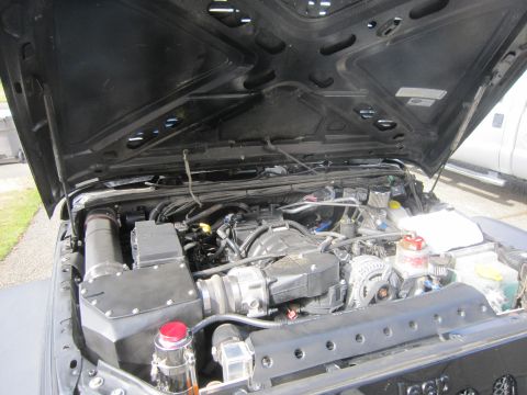 2008 Jeep Wrangler - The engine bay of a Jeep Wrangler shows a modified setup with an exposed air intake system and numerous wires and complex wiring harnesses.