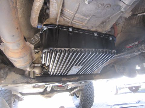 2008 Jeep Wrangler - Close-up view of a large, finned aftermarket oil pan installed on a vehicle's undercarriage.