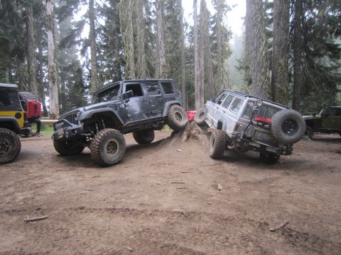 2008 Jeep Wrangler - Several off-road vehicles are shown navigating a challenging dirt trail in a wooded area.