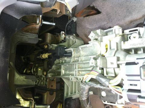 2003 Ford Crown Victoria - Close-up of a disassembled steering column area showing a cast aluminum housing with a Ford 'F6DC' casting mark, exposed shift mechanism, m…