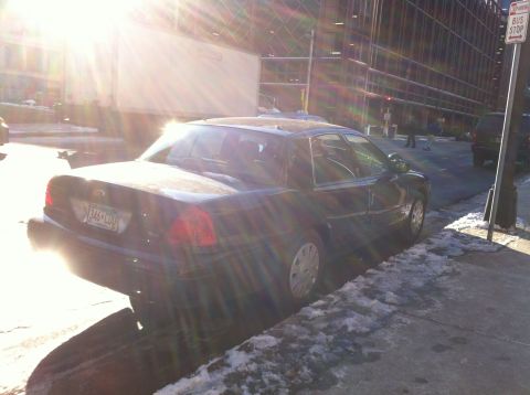 2003 Ford Crown Victoria - A dark 2003 Ford Crown Victoria is parked on the side of the road with snow on the ground.