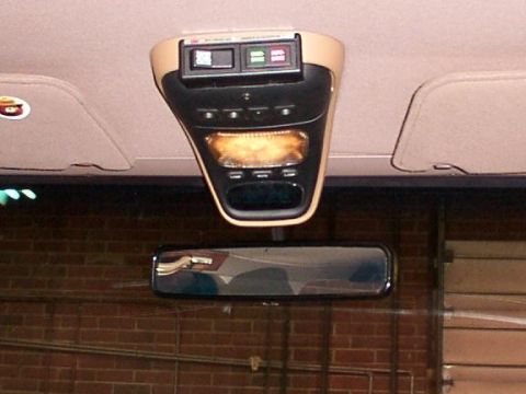 1995 Ford Bronco - Interior shot of a vehicle's overhead console and rearview mirror, with a brick wall visible in the reflection.