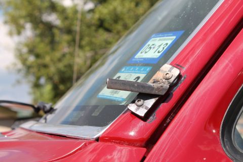 1990 Ford Bronco - A close-up view of a vehicle's windshield shows a custom-mounted bracket and inspection stickers.