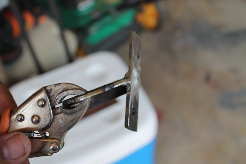 1990 Ford Bronco - Metal bracket held by locking pliers, likely for automotive repair or modification.