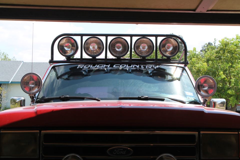 Red Ford truck front view with a "Rough Country" light bar and two side lights