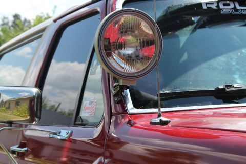 1990 Ford Bronco - Close-up of an aftermarket A-pillar light mounted on the side of a red SUV.