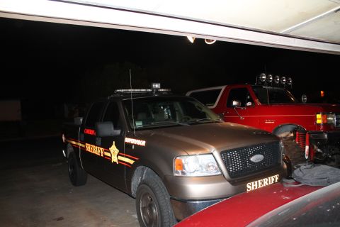 1990 Ford Bronco - A red Ford Bronco with a light bar is parked next to a sheriff's truck.
