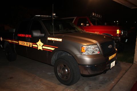 1990 Ford Bronco - Two vehicles are parked, one is a sheriff's truck and the other is a red SUV.
