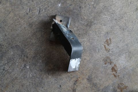 1990 Ford Bronco - A metal bracket, possibly a vehicle part, rests on a textured concrete surface.
