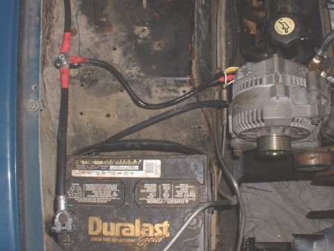 1986 Ford Bronco - Close-up view of a vehicle's engine bay, focusing on the battery and alternator components of the alternator.