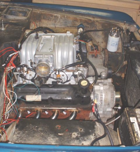 1986 Ford Bronco - The engine bay of a vehicle, showing a V8 engine with exposed wiring and various components.