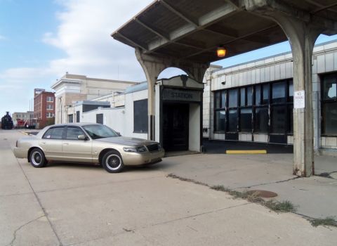 2000 Mercury Grand Marquis - A gold 2000 Mercury Grand Marquis is parked in front of a building labeled 'STATION'.