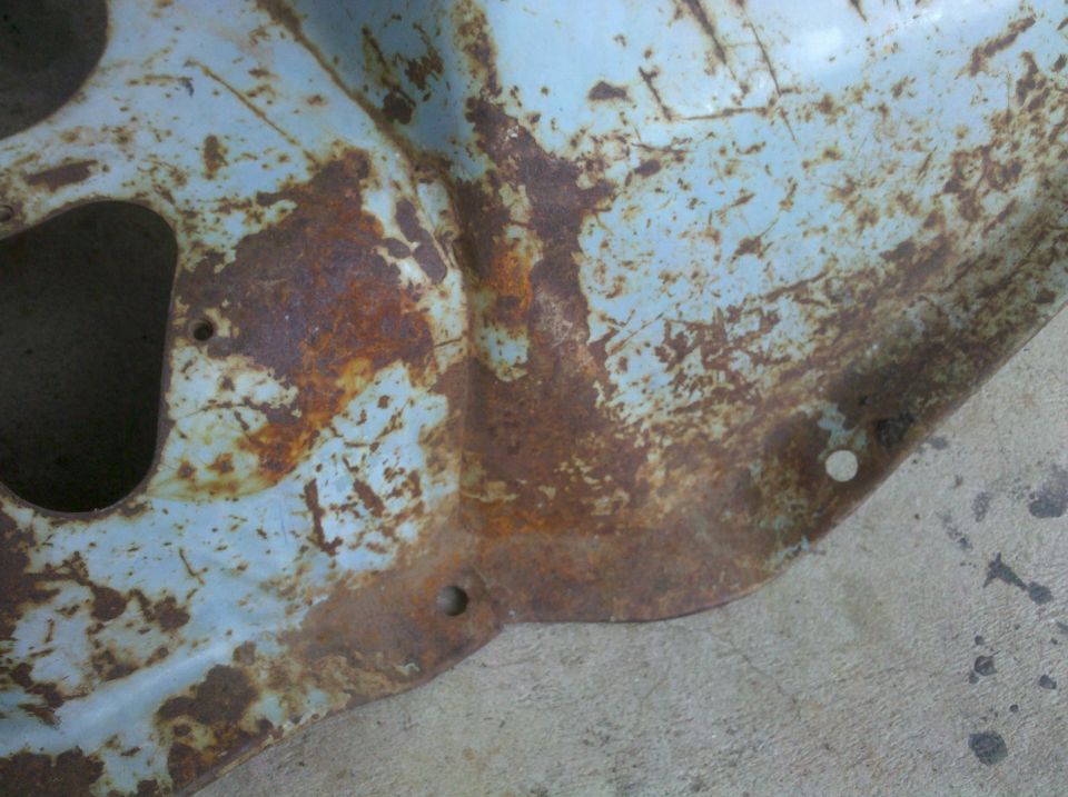 close-up of heavily rusted, light blue painted metal with holes