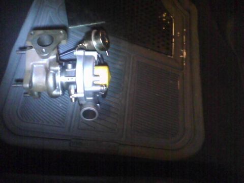 2003 Ford Crown Victoria - A turbocharger is shown resting on a black rubber floor mat inside a vehicle.