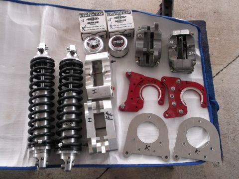 1971 Ford Ranchero - Various performance parts laid out, including shocks, brake calipers, and Weld racing center caps.