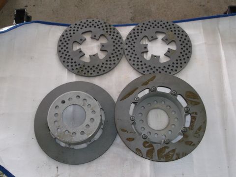 1971 Ford Ranchero - A collection of four brake rotors, two with a drilled and slotted design and two solid rotors with attached hubs, are laid out on a white s…