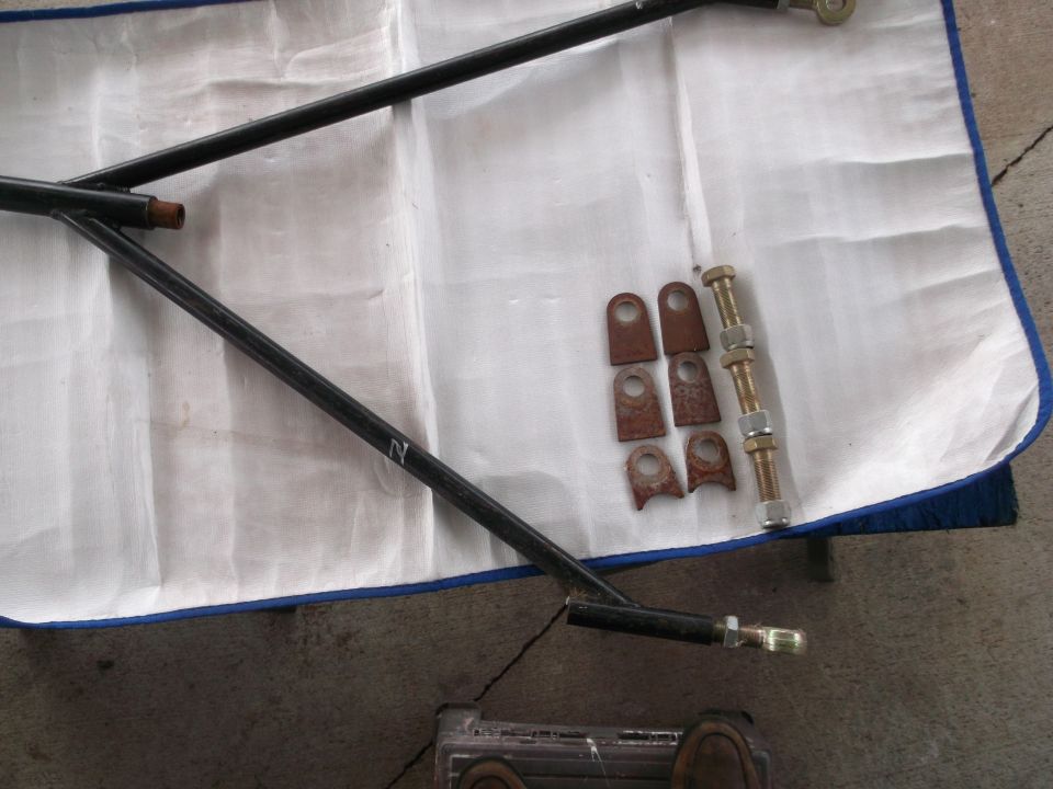 Black metal suspension arms and rusty metal brackets with bolts on a white cloth