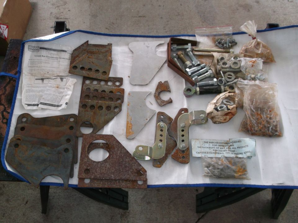 Bunch of rusty metal brackets, bolts, nuts, and some paperwork laid out on a blue tarp